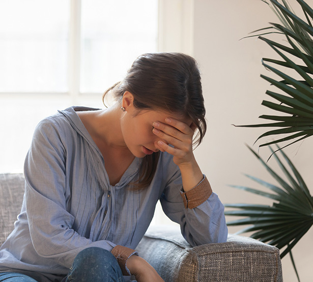 Femme assise, coude posé sur l'accoudoir du canapé et tête dans la main, semble fatiguée - MACSF