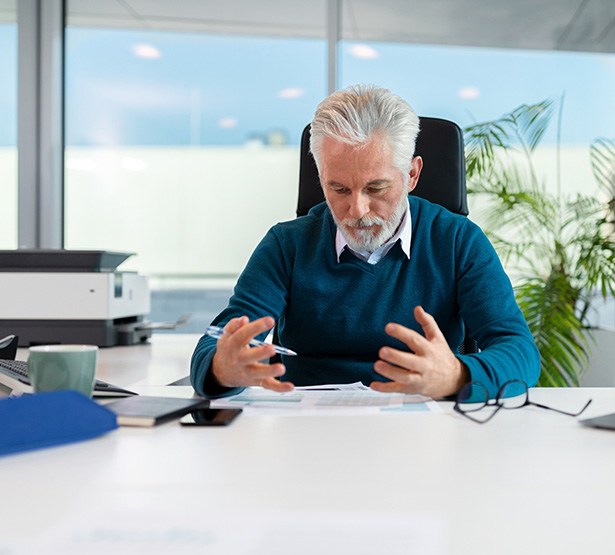 Un homme à son bureau regarde un document - MACSF