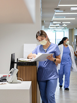 Une professionnelle de santé consulte un dossier sur le comptoir du service d'accueil de l'hopital - MACSF