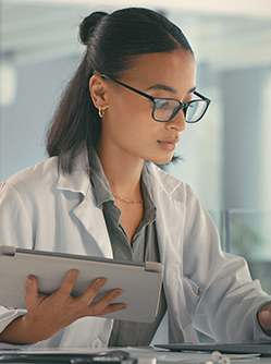 Une femme médecin face à son ordinateur tenant à la main une tablette - MACSF