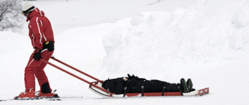 Secouriste sur piste tractant une victime en barquette - MACSF