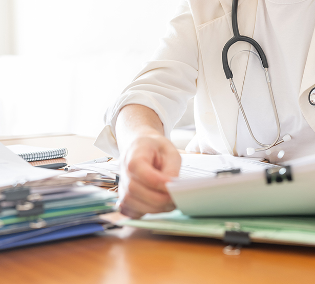 Un médecin examine une pile de dossiers de patients - MACSF