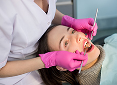 Une femme chirurgien-dentiste examine les dents d'une patiente avec des outils dentaires - MACSF