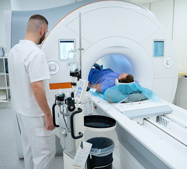 Un patient est allongé dans un scanner pendant qu’un technicien médical surveille l’examen - MACSF