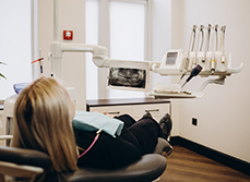 Une patiente installée dans le fauteuil dentaire face à une radio panoramique - MACSF