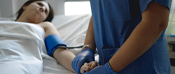 Une infirmière prend la tension d'une patiente alitée à l'hôpital - MACSF