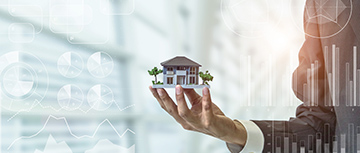 Une main tenant une maquette de maison avec des statistiques en filigrane - MACSF