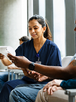 Une infirmière aide un patient à remplir un questionnaire en salle d'attente - MACSF