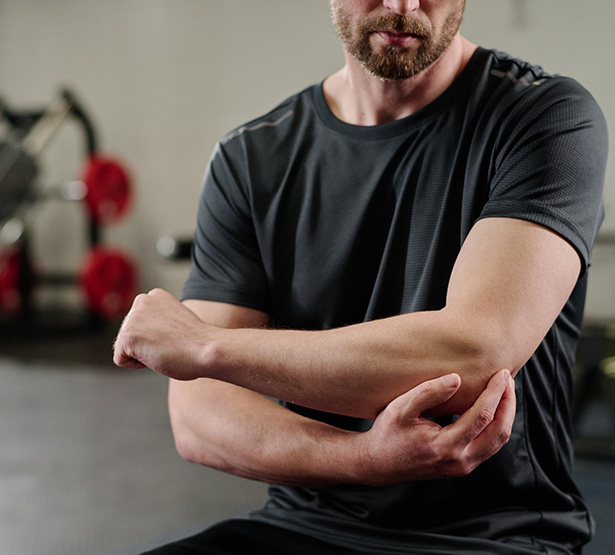 Un homme assis dans la salle du kinésithérapeute se tient le coude - MACSF