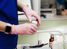 Gros plan sur les mains gantées d'une technicienne de laboratoire tenant un flacon de prélèvement - MACSF
