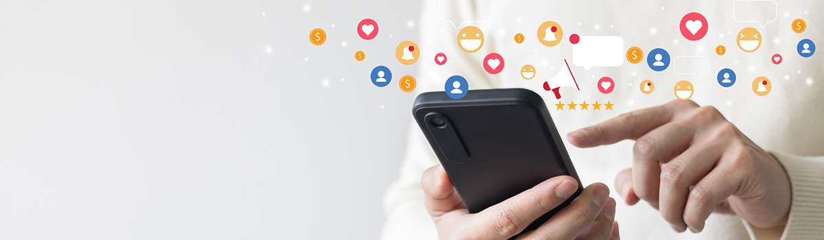 gros plan sur une main pianotant sur un smartphone, entourés d'un nuage de smileys - MACSF