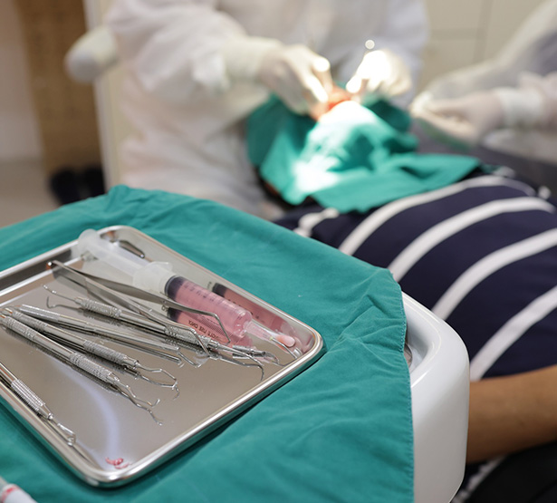 Chirurgien-dentiste pratiquant des soins et plateau d'instruments dentaires - MACSF