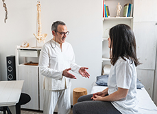 Un kinésithérapeute apporte des explications à une patiente - MACSF