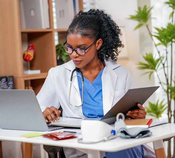 Une femme médecin consulte son ordinateur dans son cabinet - MACSF