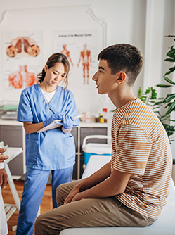 Un médecin discute avec un patient adolescent pendant qu'une infirmière prend des notes - MACSF