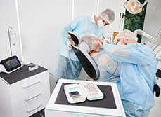 Une patiente sur le fauteuil du dentiste entourée de deux praticiens - MACSF