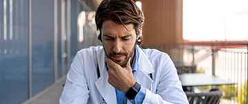 Un professionnel de santé regarde son smartphone d'un air soucieux - MACSF
