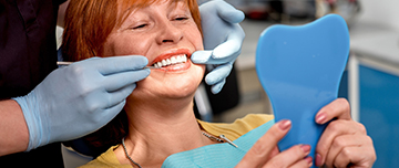 Tenant un miroir, la patiente regarde ses prothèses dentaires - MACSF