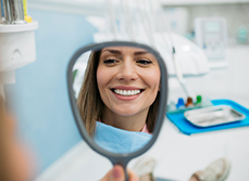 Une jeune femme souriante devant le miroir chez le dentiste - MACSF