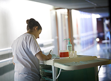 Une infirmière dans un couloir note les soins effectués - MACSF