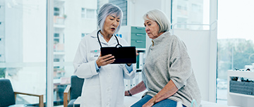 Deux femmes d'âge mûr, patiente et médecin, contrôlent des résultats médicaux sur une tablette - MACSF