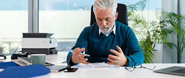 Un homme à son bureau regarde un document - MACSF