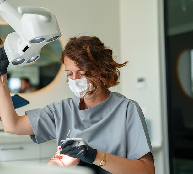 Une femme chirurgien-dentiste pratique des soins sur une patiente - MACSF