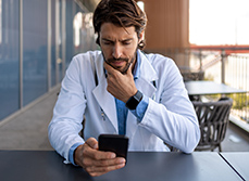 Un professionnel de santé regarde son smartphone d'un air soucieux - MACSF