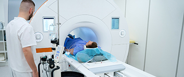Un patient est allongé dans un scanner pendant qu’un technicien médical surveille l’examen - MACSF