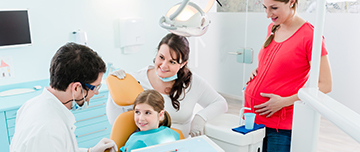 Dentiste en consultation avec une jeune patiente accompagnée de sa mère enceinte - MACSF