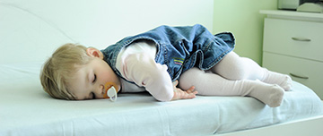 Une petite fille dort sur le bord d'un lit - MACSF