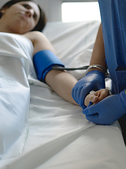 Une infirmière prend la tension d'une patiente alitée à l'hôpital - MACSF