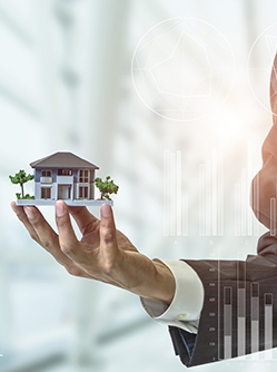 Une main tenant une maquette de maison avec des statistiques en filigrane - MACSF