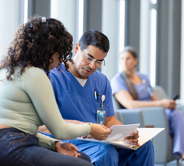 Un infirmier parle avec une patiente dans la salle d'attente de l'hôpital - MACSF