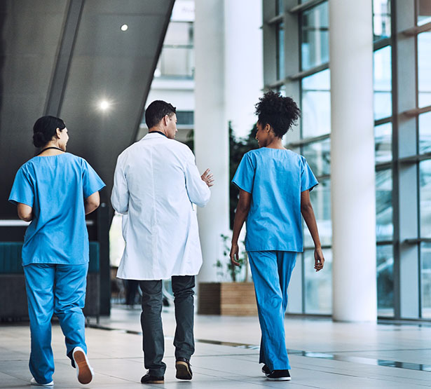 Trois professionnels de santé marchent dans le hall d'un hôpital - MACSF