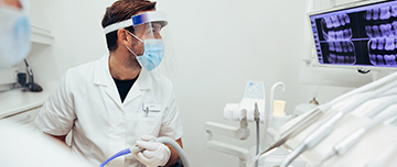 Un chirurgien dentiste observe la radiographie à l'écran - MACSF