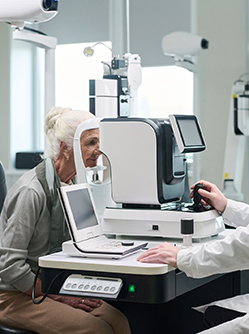 Une femme âgée fait un examen à l'aide de matériel ophtalmologique - MACSF