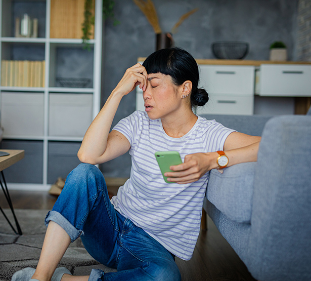 Une femme désabusée avec un smartphone dans la main - MACSF