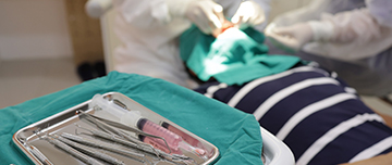 Chirurgien-dentiste pratiquant des soins et plateau d'instruments dentaires - MACSF