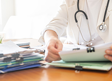 Un médecin examine une pile de dossiers de patients - MACSF