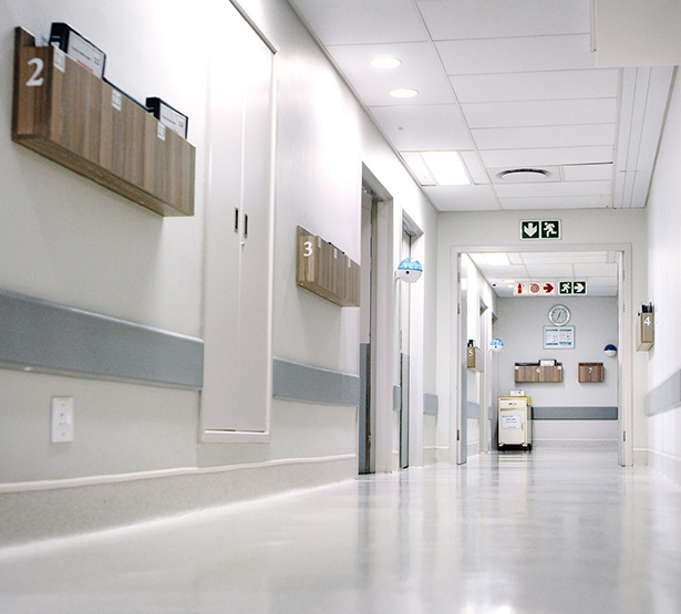 Des dossiers patients dans des bannettes accrochées au mur d'un couloir d'hôpital - MACSF