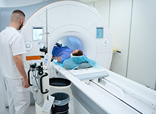 Un patient est allongé dans un scanner pendant qu’un technicien médical surveille l’examen - MACSF