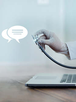 Une main de médecin tenant un stéthoscope sort de l'écran d'un ordinateur portable - MACSF