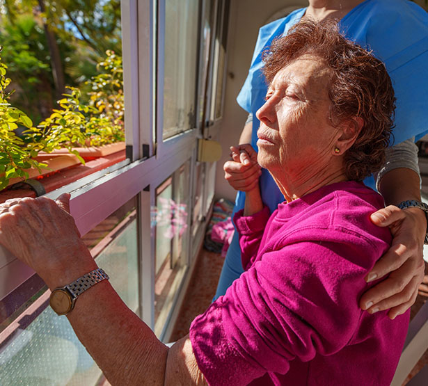 Une femme âgée assise près de la fenêtre avec la soignante - MACSF