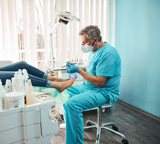 Un pédicure-podologue réalise des soins sur une patiente - MACSF