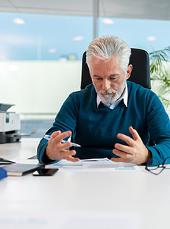 Un homme à son bureau regarde un document - MACSF