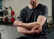 Un homme assis dans la salle du kinésithérapeute se tient le coude - MACSF