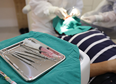 Chirurgien-dentiste pratiquant des soins et plateau d'instruments dentaires - MACSF