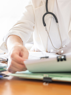 Un médecin examine une pile de dossiers de patients - MACSF