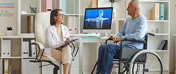 Une femme médecin en consultation avec une homme en fauteuil roulant - MACSF